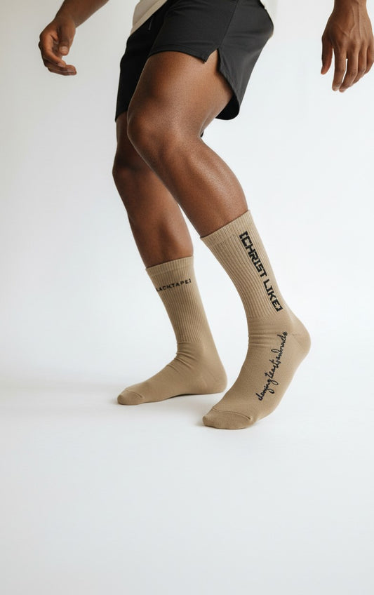 Blacktapechamchristlike Potter's Clay crew socks in beige cotton with black embroidered text on a model