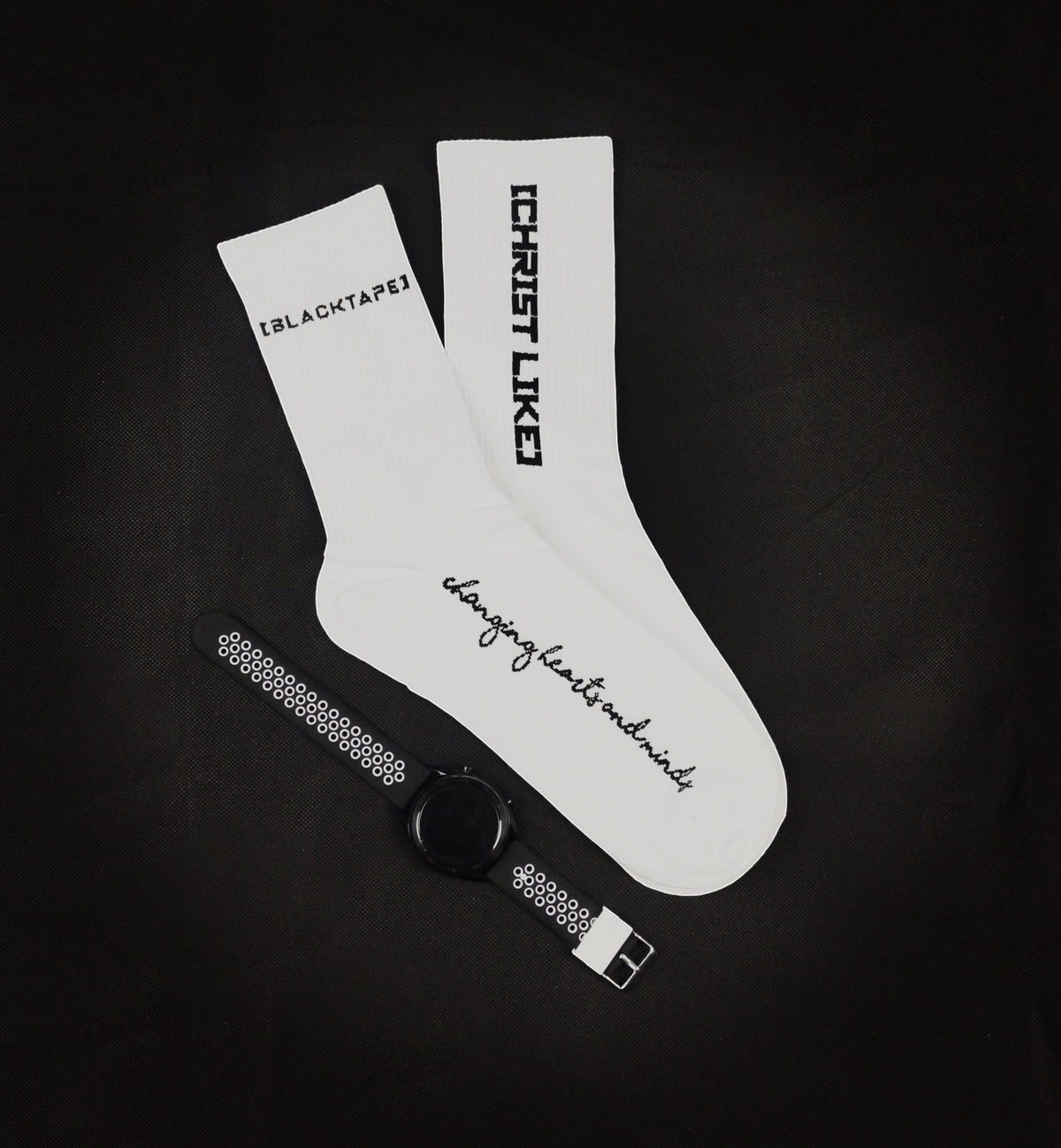 Blacktapechamchristlike white cotton crew socks with black embroidery text and a matching smartwatch on black background